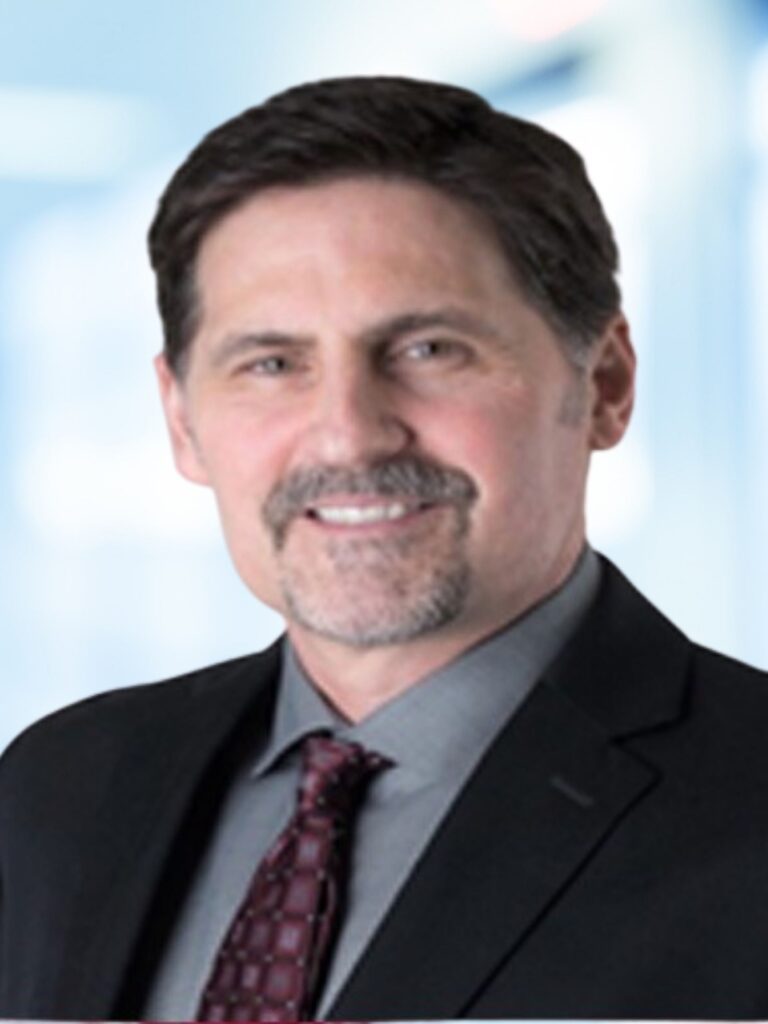 A smiling man in a suit and tie, representing professionalism and expertise in integrative medicine.